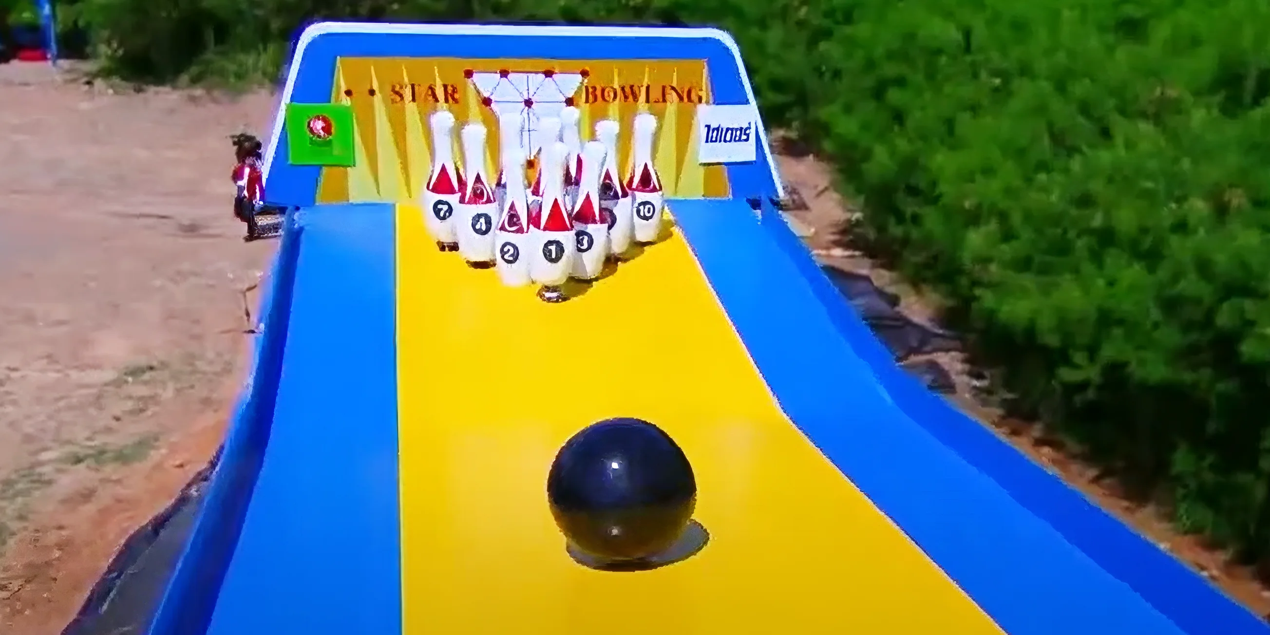 10 players dressed as giant bowling pins prepare to be hit by a huge bowling ball